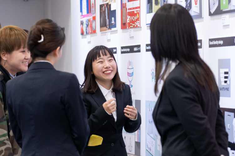 作品展示会で来場者に説明を行う学生